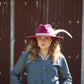 Woman wearing a magenta hat with a feather and pearl necklace.