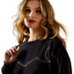 Woman in black sweatshirt with gold detail, F25_WMS_WEST