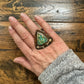 Hand wearing turquoise ring with arrow details.
