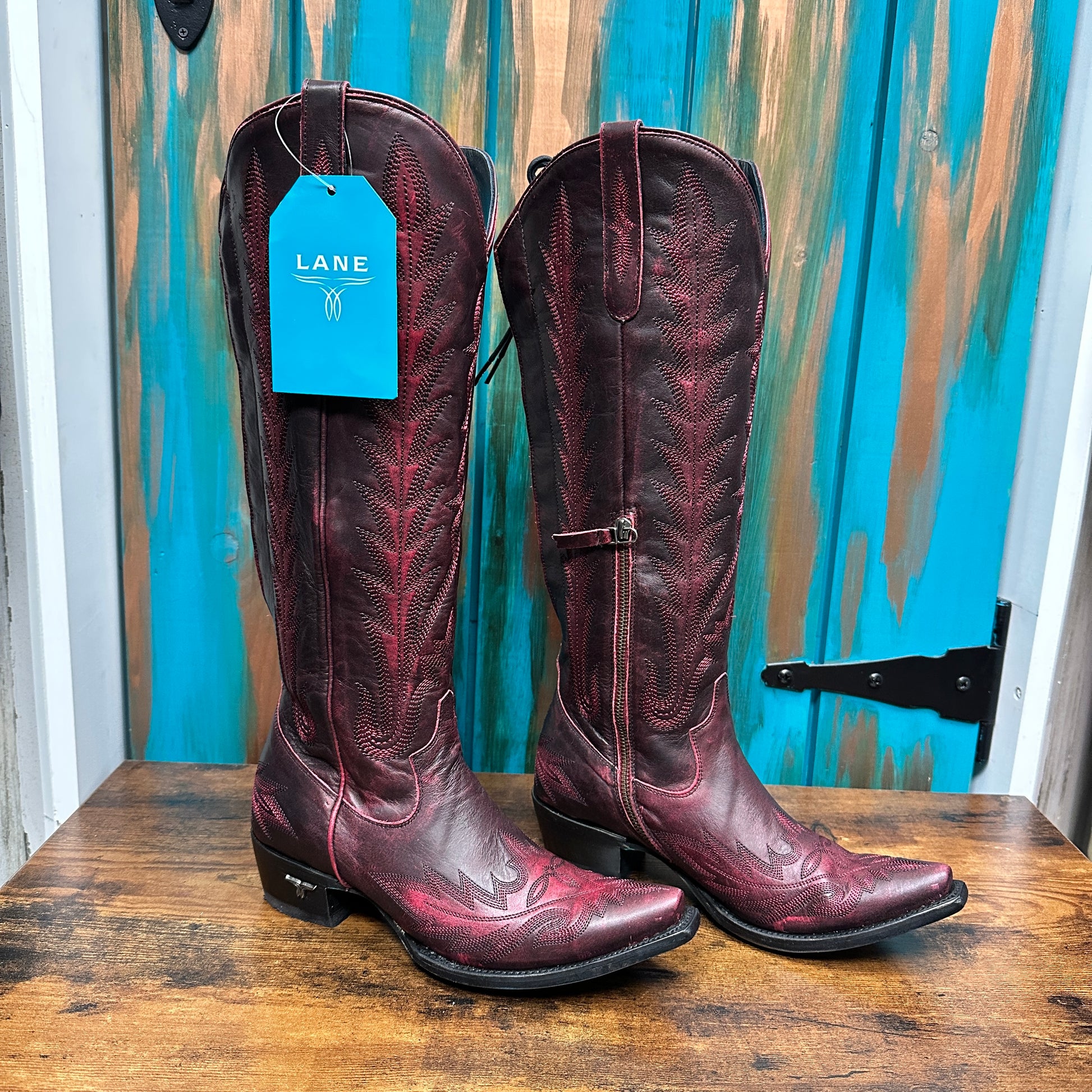 Pair of tall, red cowboy boots with tags.