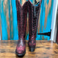 Red leather cowboy boots on wooden surface.