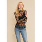 Woman in sheer top and jeans smiling.