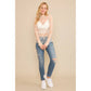 Woman wearing lace top, jeans, and sneakers.