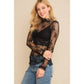 Woman wearing a black lace top and jeans.