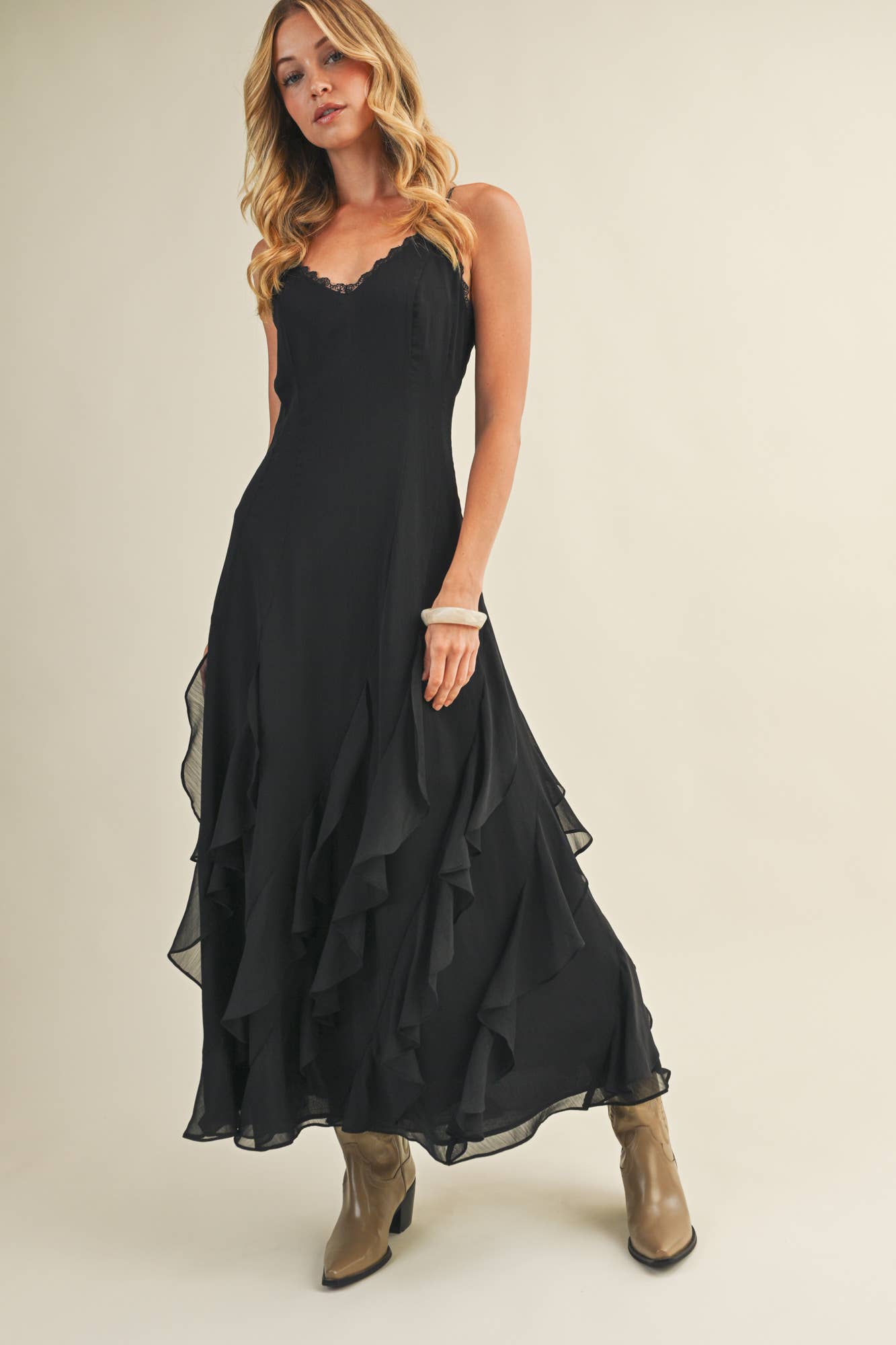 Woman in black dress with ruffles and spaghetti straps.