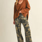 Woman in sweater, camo pants, and cap.