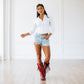 Woman in white shirt, denim shorts, and ruby red boots