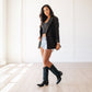 Woman in black blazer, denim shorts & Carbon Croc cowboy boots.